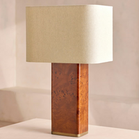 The Remi table lamp by Soho Home. Designed with a rectangular base in dark oak mappa burl timber. Complemented with a natural linen shade. Inspired by Soho House.